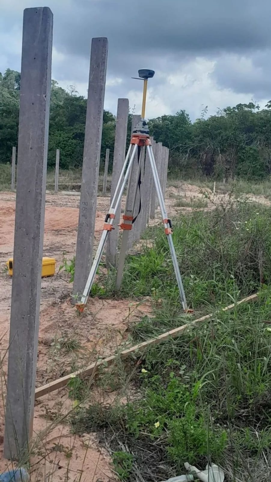 Equipamento de geodésia em terreno com postes de concreto