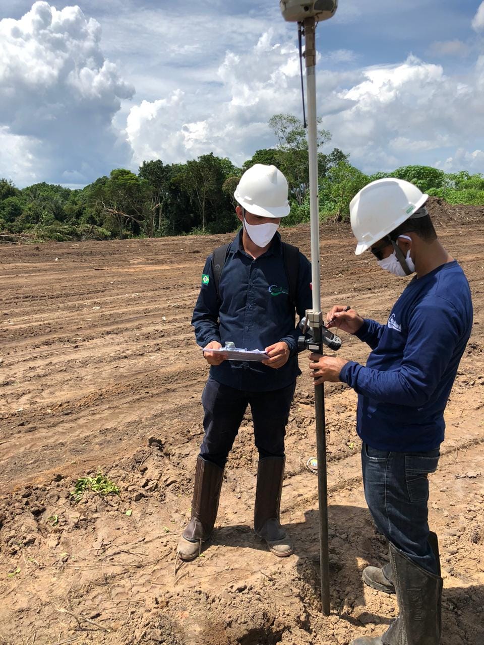 Equipe com antena GPS em terreno de terra