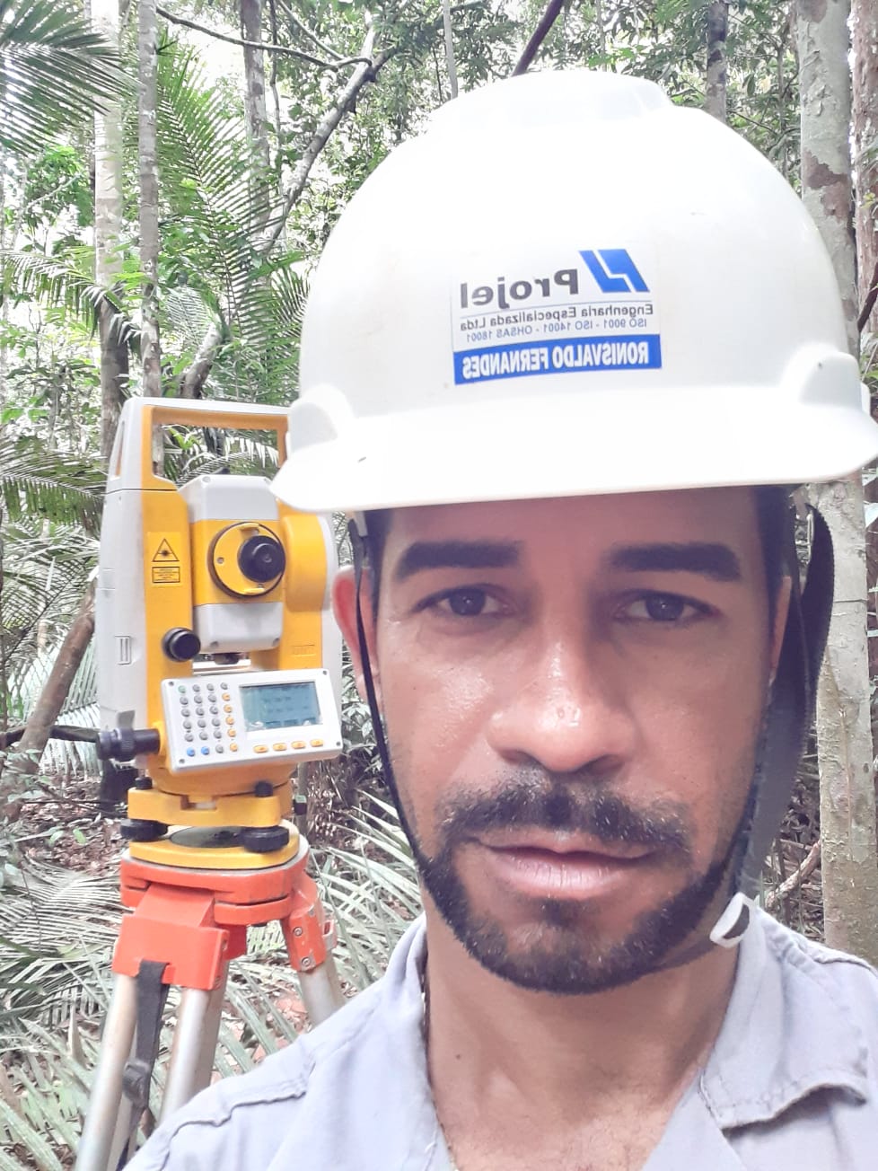 Profissional com equipamento topográfico em área de floresta